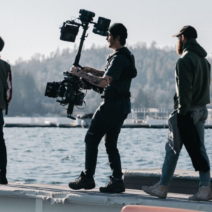 three people people staining near water holding filming equipment
