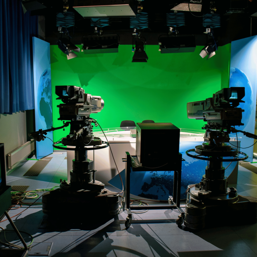 Television cameras pointing at a presenter's desk and greenscreen.
