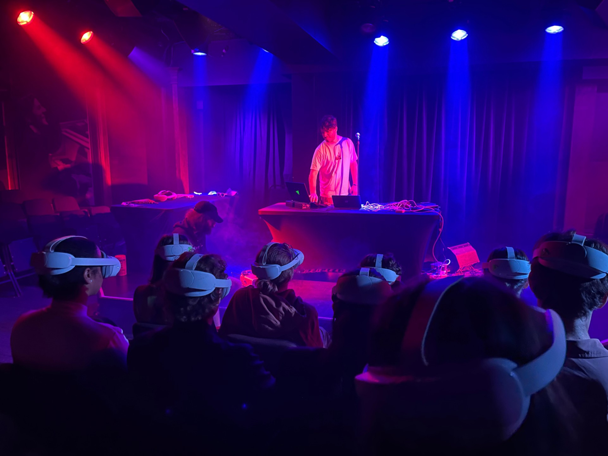 man performing on stage, people watching with VR headsets