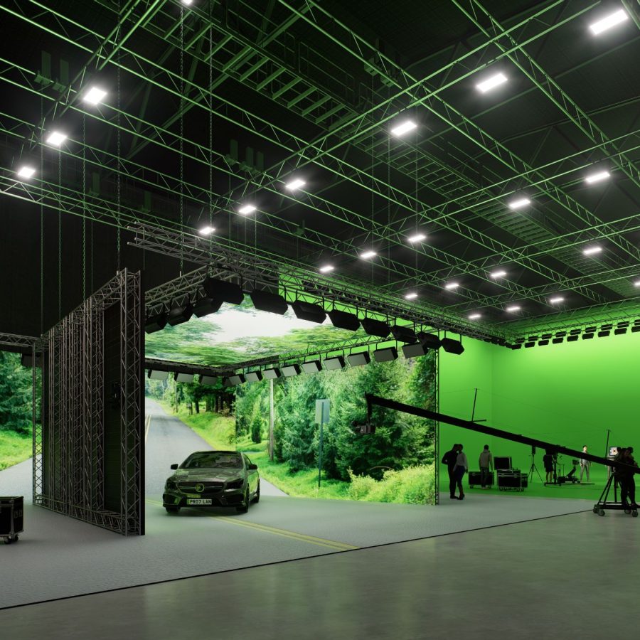 studios with a large green screen, there is a lighting rig on the ceiling and a car, TV crew and people in the green screen