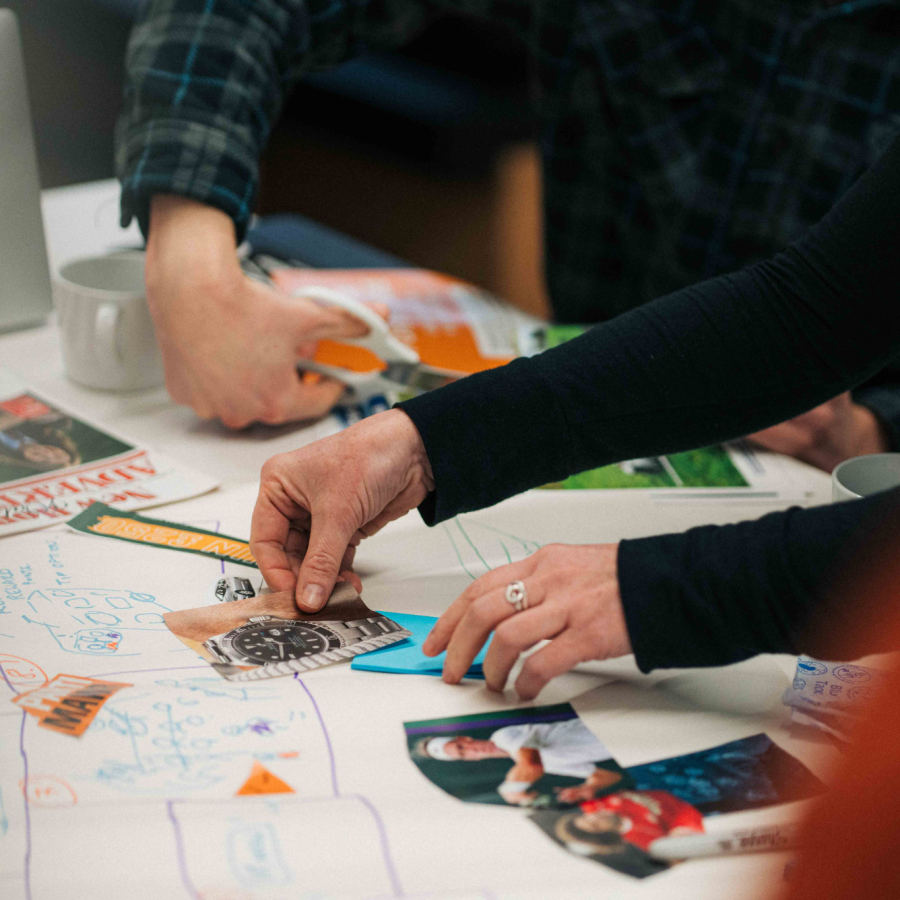 people's hands holding rulers and putting images and post it notes on pieces of paper