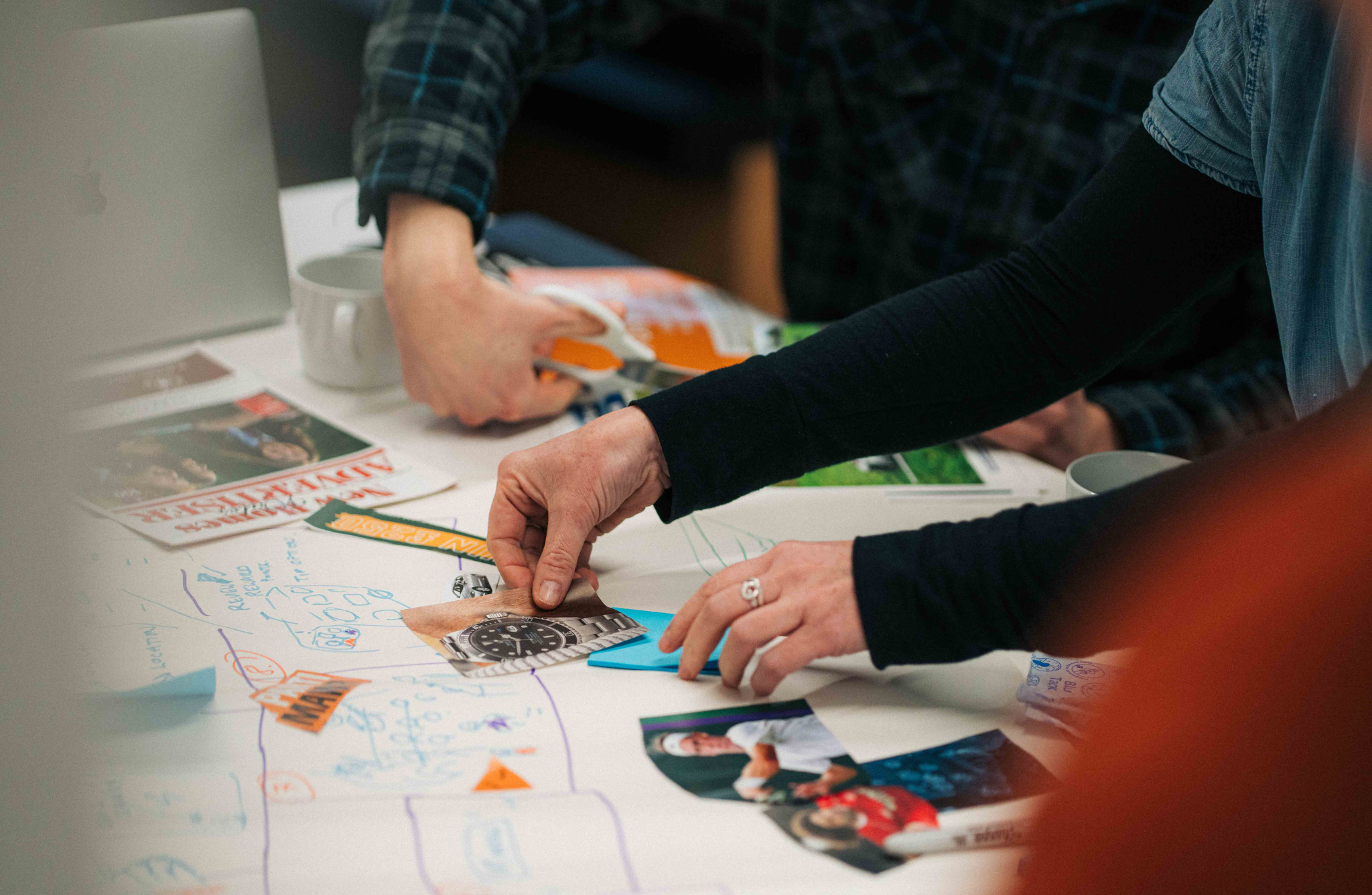 people's hands holding rulers and putting images and post it notes on pieces of paper