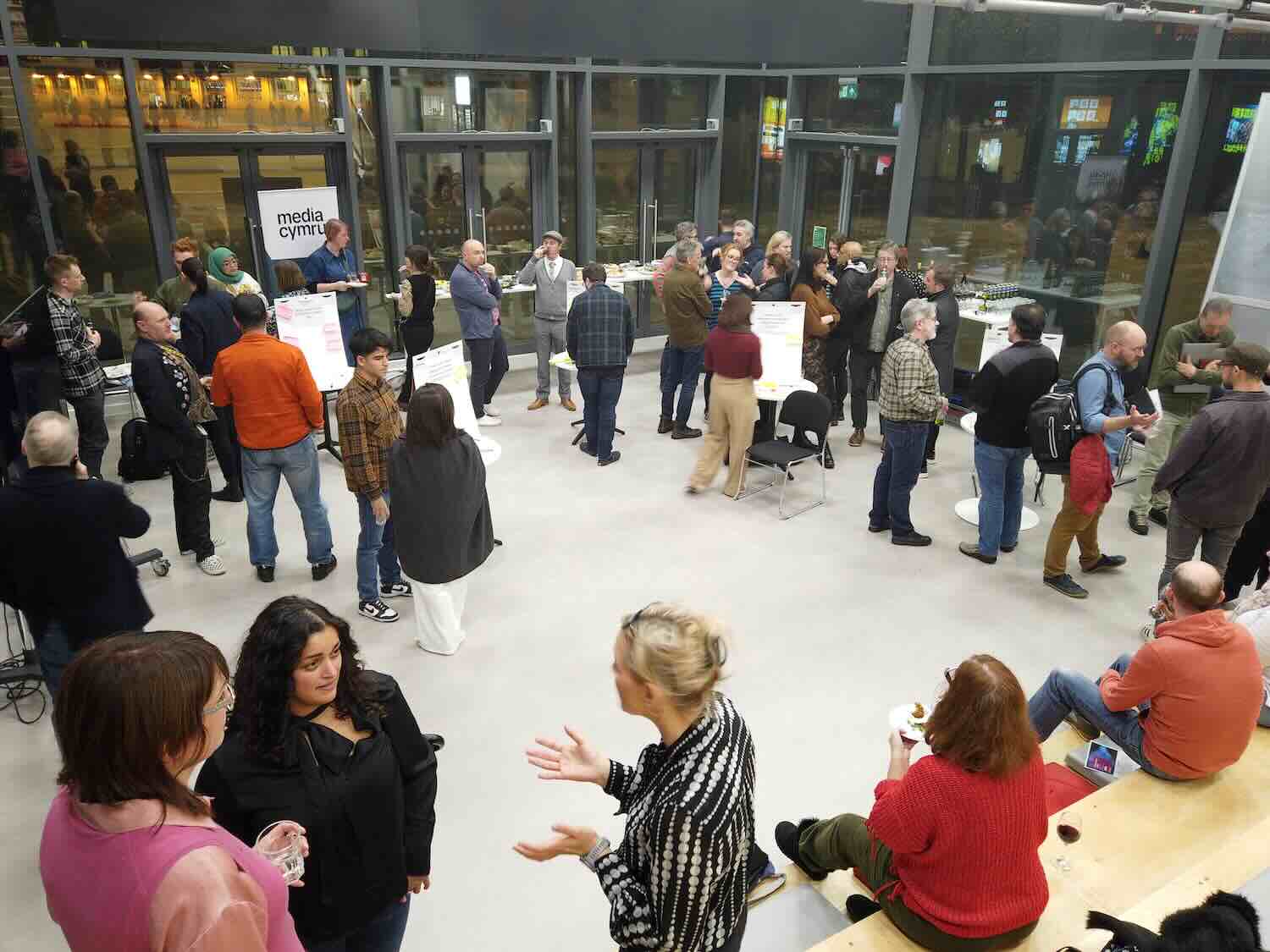A bustling XR Network+ event in Cardiff, with people standing around chatting and a Media Cymru banner up